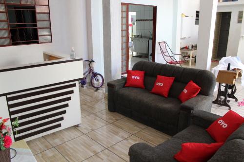 a living room with two couches and red pillows at OYO Pousada Paraná in Cuiabá