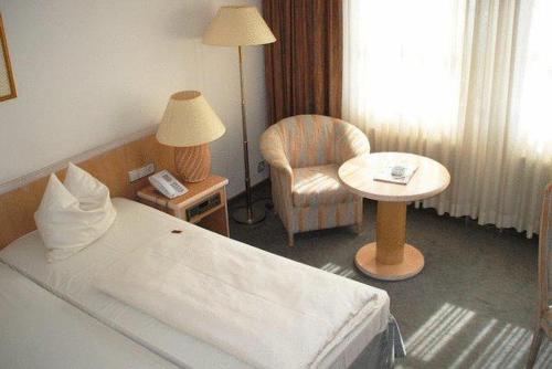 a hotel room with a bed and a chair at Landhotel Burkartsmühle in Hofheim am Taunus