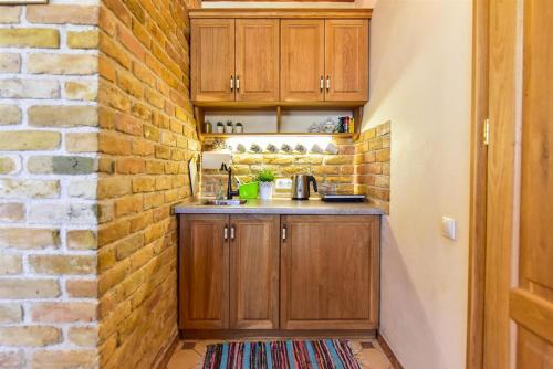 a kitchen with wooden cabinets and a brick wall at Country Home in Ventspils