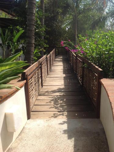a wooden bridge leading to a garden with pink flowers at Casa Flor de Mar in Zipolite