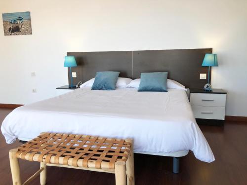 a bedroom with a large white bed and a bench at Cotillo Ocean View in Cotillo