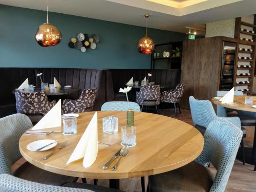 a wooden table and chairs in a restaurant at Hotel Berg en Dal in Epen