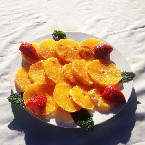 a plate of oranges and strawberries on a table at Riad Tizwa Marrakech in Marrakech