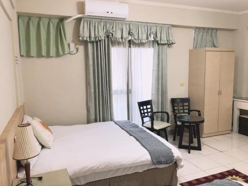 a bedroom with a bed and chairs and a window at Xin Homestay in Luodong