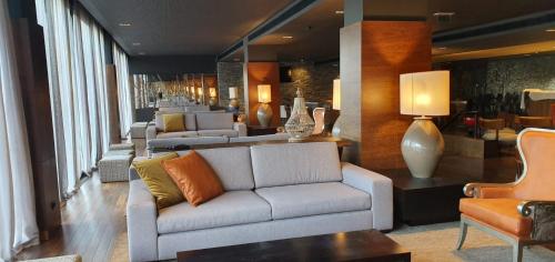 a living room filled with furniture and a large window at H2otel Congress & Medical SPA in Unhais da Serra