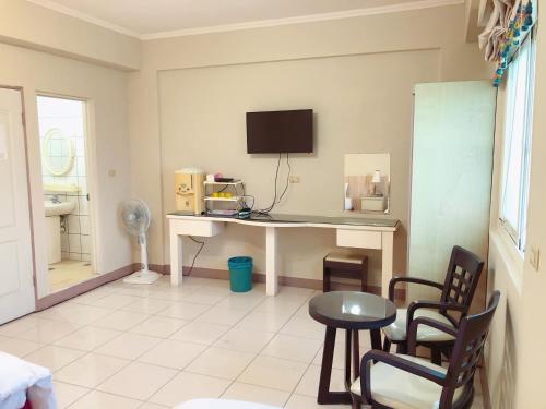 a room with a desk with a television and chairs at Xin Homestay in Luodong