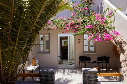 a courtyard with chairs and a tree with pink flowers at Marillia Village in Perivolos