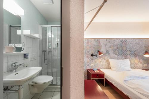 y baño con cama, lavabo y ducha. en Bären Self Check-in Hotel, en Solothurn