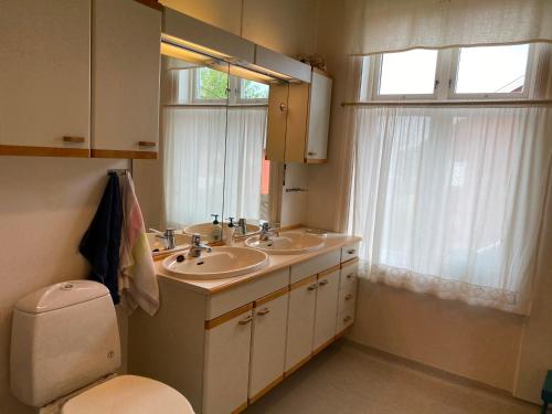 een badkamer met 2 wastafels, een toilet en een raam bij Nedre Eie in Lunde