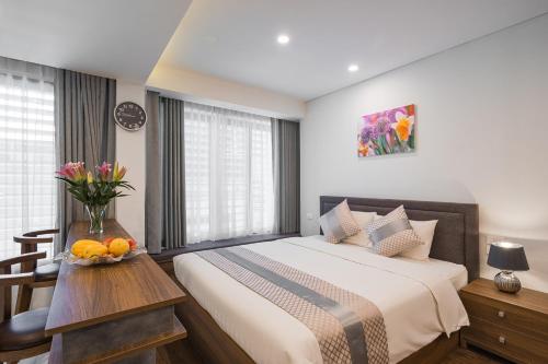 a bedroom with a bed and a vase of fruit on a table at Narcissus Hotel & Apartment in Hanoi