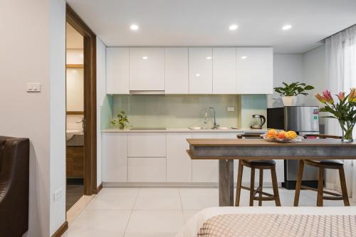a kitchen with white cabinets and a island with bar stools at Narcissus Hotel & Apartment in Hanoi