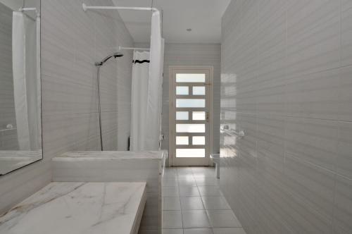 a white bathroom with a tub and a shower at Villa Cala Trons in Lloret de Mar