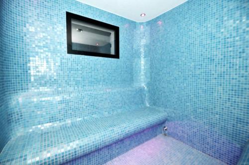 a blue tiled bathroom with a television on the wall at Morze, Basen&SPA i Spokój Apartament Pięć Mórz w Sianożętach in Sianozety
