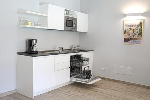 a white kitchen with a sink and a microwave at House & Pool in Mergozzo