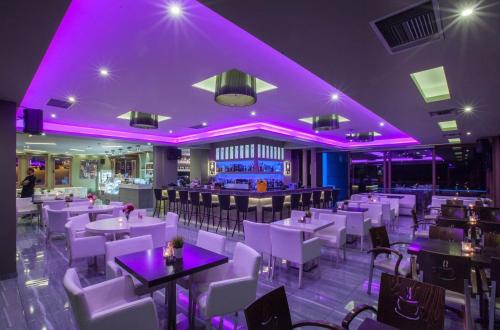 エピダウロス古代劇場にあるSTORK Design Suitesの白いテーブルと椅子、紫色の照明が備わるレストラン