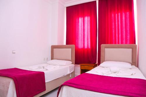 2 łóżka w pokoju z czerwonymi zasłonami w obiekcie Villa Ali Ozalp w mieście Dalyan