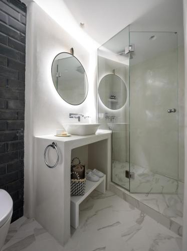 a white bathroom with a sink and a shower at Villa Renos Hotel in Fira