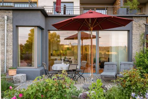 a patio with a table and an umbrella at Lebensart am See in Bad Endorf