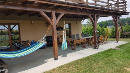 a patio with a hammock and a table and chairs at Dom letniskowy Sieraków in Sieraków