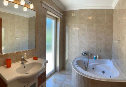 a bathroom with a tub and a sink and a mirror at Sleep & Surf Ericeira - Portugal in Ericeira