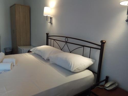 a bed with a white comforter and pillows at Delfini Hotel in Piraeus