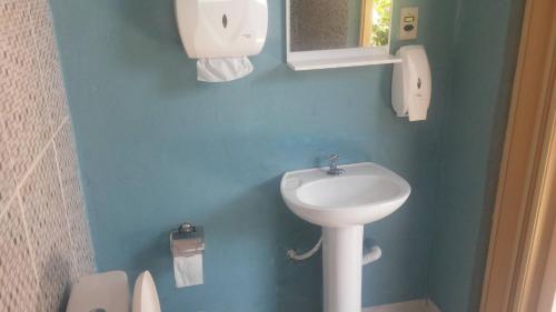 Baño azul con lavabo y aseo en Cozy House Booking Indaiatuba, en Indaiatuba