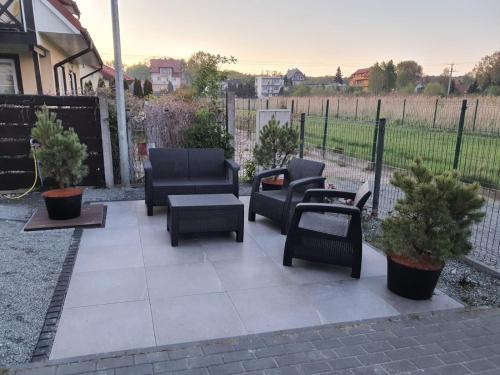 a patio with chairs and tables and a fence at Los Reyes II - klimatyzowane pokoje in Krynica Morska