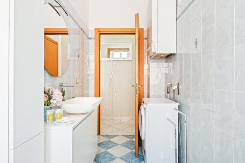 a white bathroom with a sink and a mirror at Giardino Vignoli Functional Apartment in Bologna