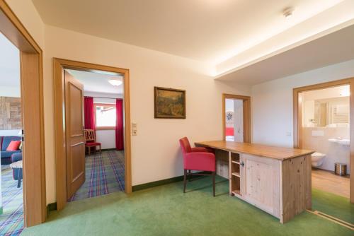 a room with a desk and red chairs at Relais & Châteaux Gut Steinbach Hotel Chalets SPA in Reit im Winkl