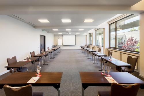 a dining room with tables and chairs and a whiteboard at Ramada Plaza by Wyndham Bucharest Convention Center in Bucharest