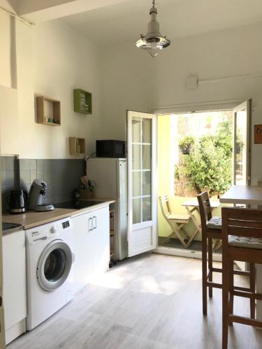 une cuisine avec une machine à laver et une table dans l'établissement Grand F2 quartier Les Plaines, Boulouris proche mer et port Santa-Lucia, à Saint-Raphaël