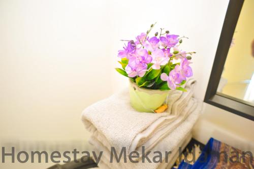a vase filled with purple flowers sitting on a towel at homestay mekar idaman in Kepala Batas