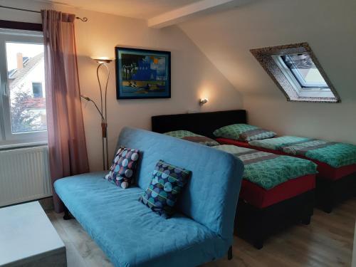 Cette chambre comprend deux lits, un canapé et une fenêtre. dans l'établissement Ferienwohnung Jasmin, à Hanovre