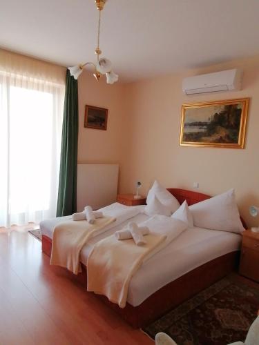 a bedroom with two beds and a large window at Erika Apartmanházak in Hévíz