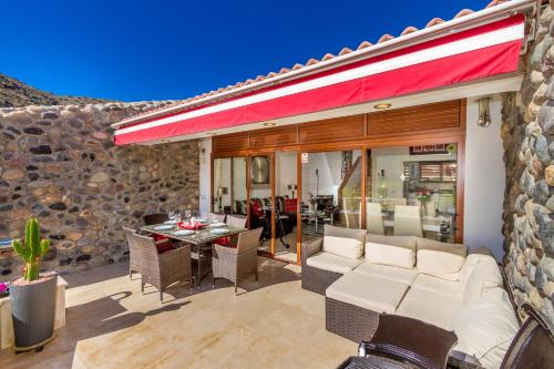 a patio with a couch and a table at Casa Holmston, Duplex villa with hot tub in Anfi Tauro Topaz in Mogán