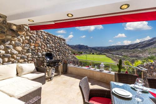 a patio with a couch and chairs and a stone wall at Casa Holmston, Duplex villa with hot tub in Anfi Tauro Topaz in Mogán