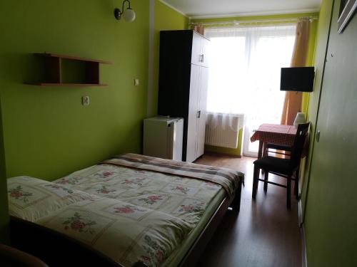 a green bedroom with a bed and a chair at Róża Wiatrów 2 Władysławowo in Władysławowo