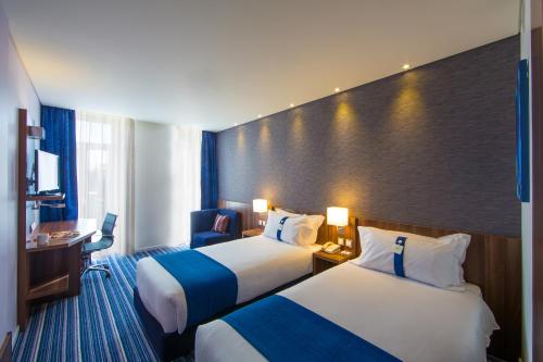 リスボンにあるHoliday Inn Express Lisboa - Av. Liberdade, an IHG Hotelのベッド2台とデスクが備わるホテルルームです。