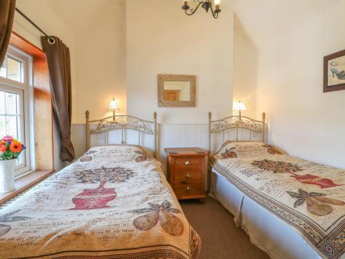 a bedroom with two beds and a window at Lees Moor Cottage in Matlock