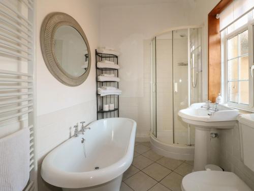 a bathroom with a tub and a sink and a mirror at Lees Moor Cottage in Matlock
