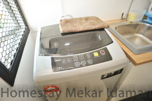a washing machine in a kitchen next to a sink at homestay mekar idaman in Kepala Batas