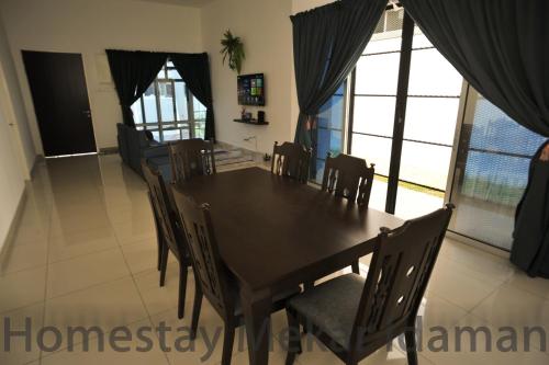 a dining room with a wooden table and chairs at homestay mekar idaman in Kepala Batas