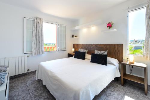 a bedroom with a white bed and two windows at Sa Carroca Villa in Sant Josep de Sa Talaia