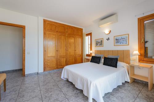 a bedroom with a white bed and wooden cabinets at Sa Carroca Villa in Sant Josep de Sa Talaia