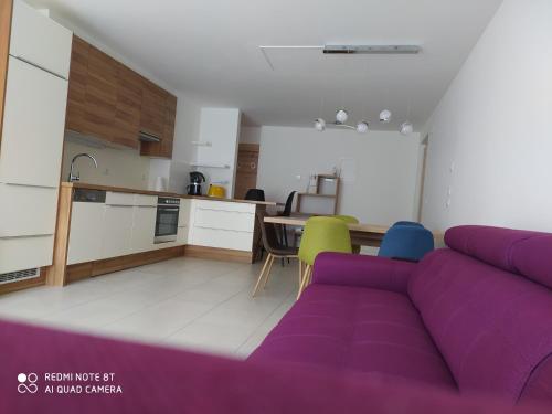 sala de estar con sofá púrpura y cocina en Appartement Nadia, en Bresanona