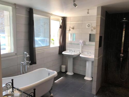 a bathroom with a tub and two sinks and a bath tub at Logis Hotel Grangier in Saint-Sozy