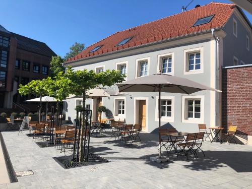 Gasthof Alter Markt في لوسهايم: مجموعة طاولات وكراسي مع مظلات امام المبنى
