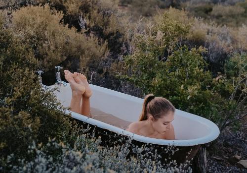 una mujer tumbada en una bañera en un campo en Simonskloof Mountain Retreat, en Montagu