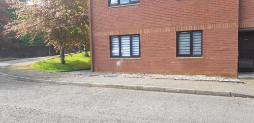 a brick building with two windows next to a street at Flat 18 in Dumfries