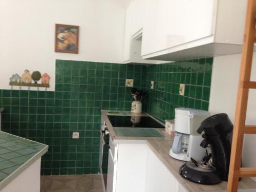 a green tiled kitchen with white cabinets and green tiles at Maison Majorelle in Moussoulens
